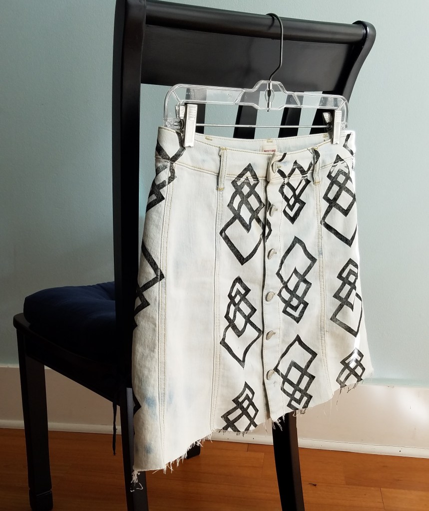 printed denim skirt hangs from back of chair