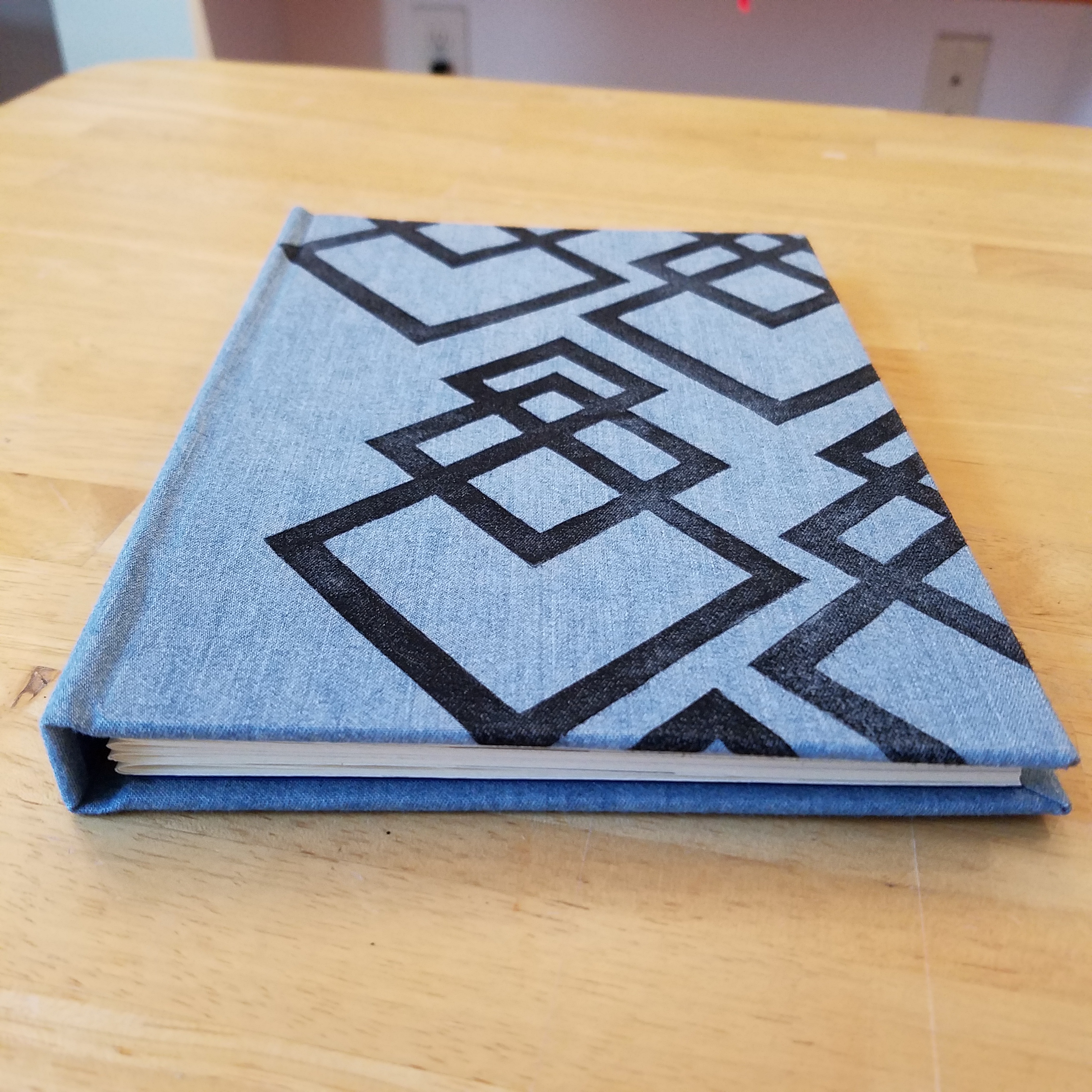 A hardcover printed book sits on a wooden table.
