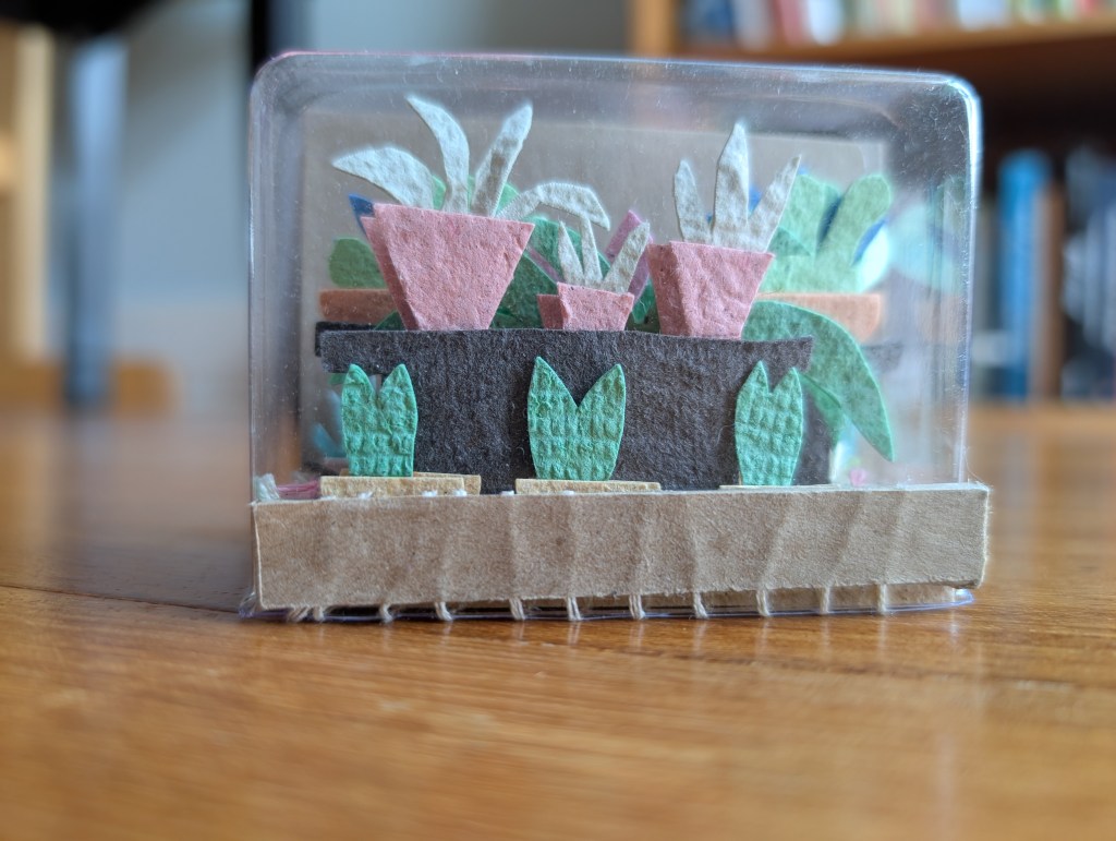 The garden variety book is seen from the front, plastic cover around the pages like a greenhouse.